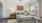 Model bedroom at our apartments for rent in Jenks, OK, featuring wood grain floor paneling and windows with curtains.