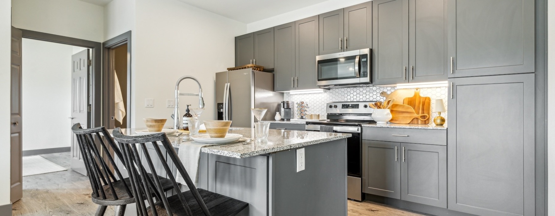 Model kitchen at our apartments for rent in Jenks, OK, featuring wood grain floor paneling and a kitchen island.